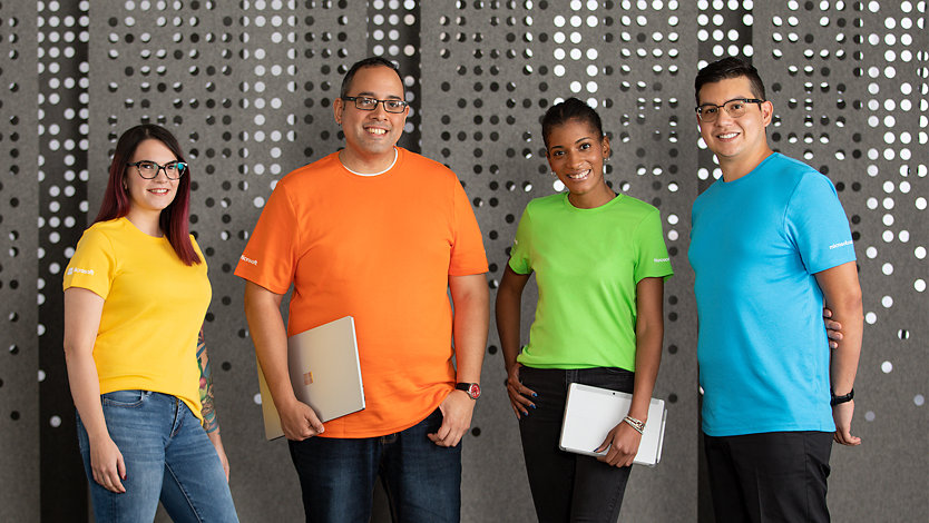 Four Microsoft Experience Center associates in colorful uniform shirts.