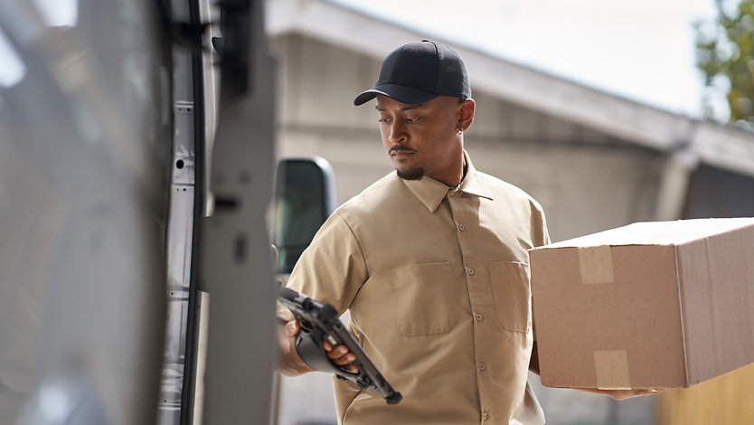 A person removing a package from delivery truck.