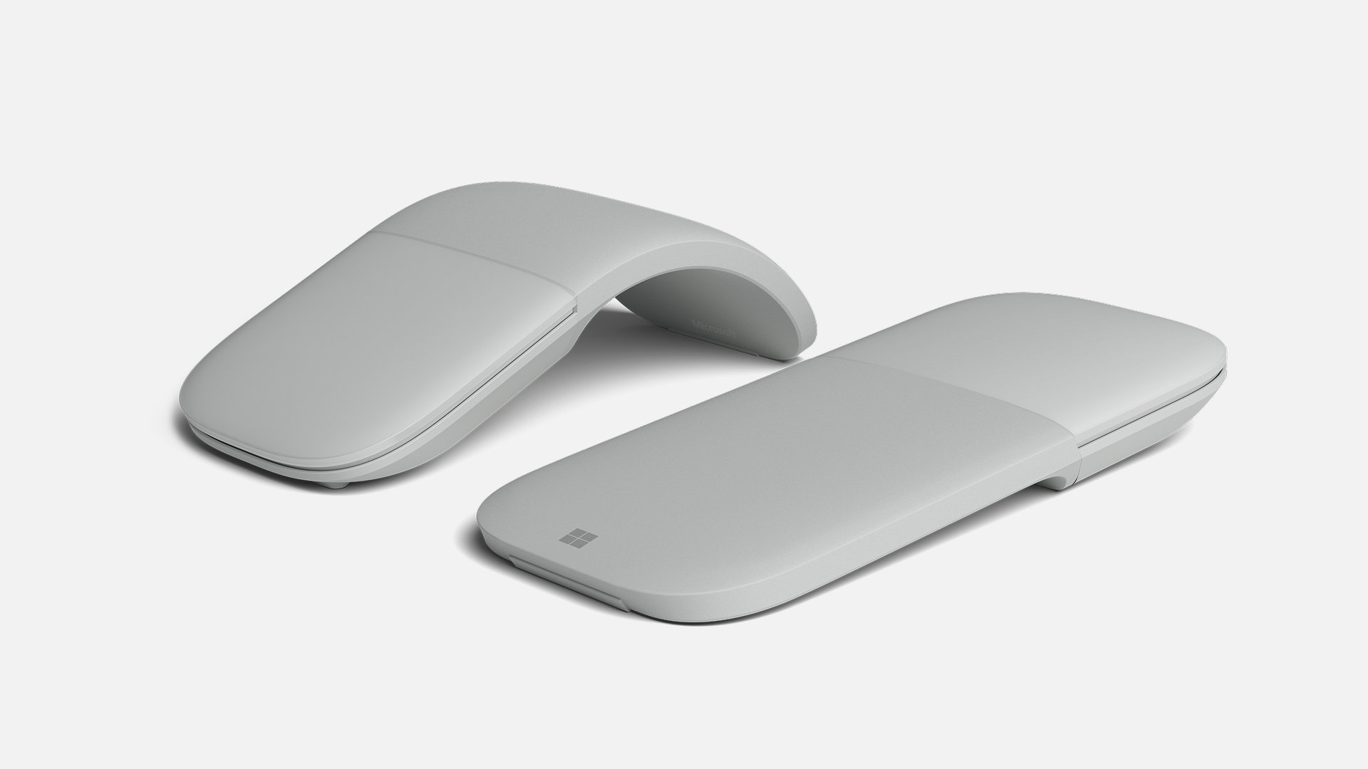 Two Light Gray Surface Arc Mouse devices, one snapped flat and the other snapped into its curved position.