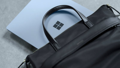 Un appareil Surface Laptop partiellement dissimulé dans une sacoche d’ordinateur portable en cuir.