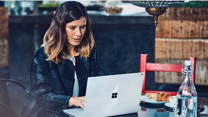 Uma mulher está sentada em um restaurante usando um computador da Microsoft.