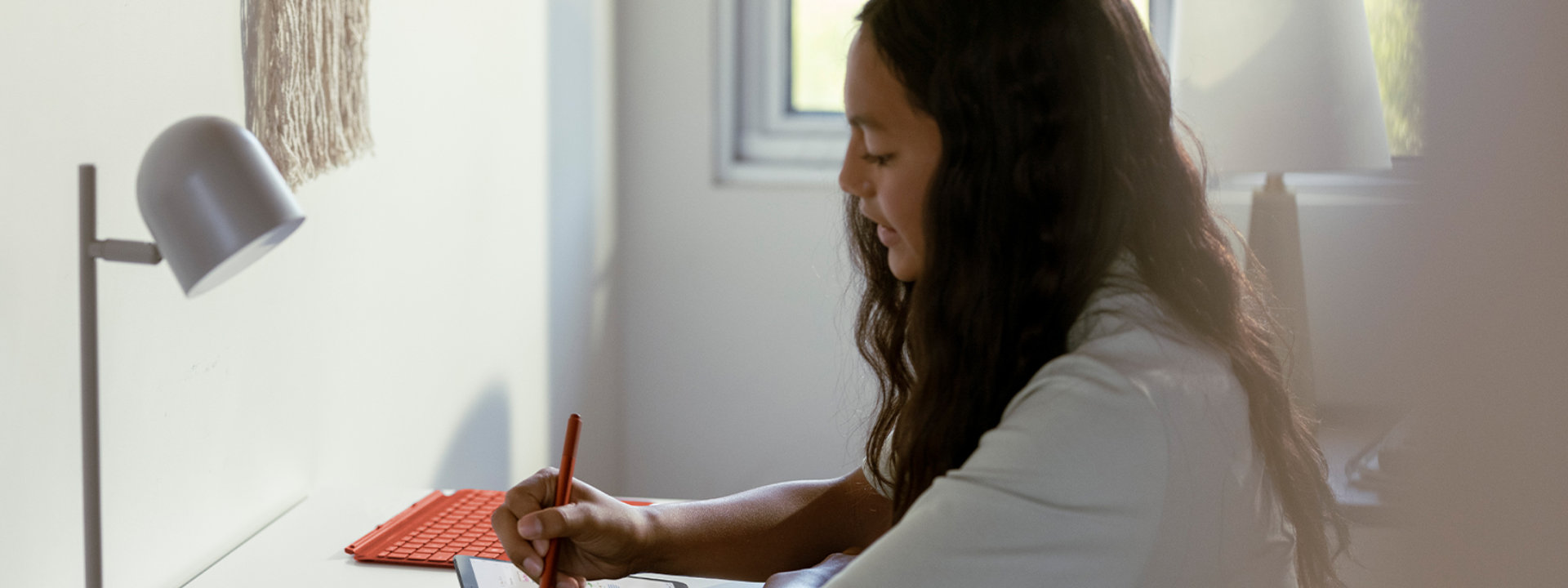 A child uses Surface Go 3 and Surface Pen at a desk.