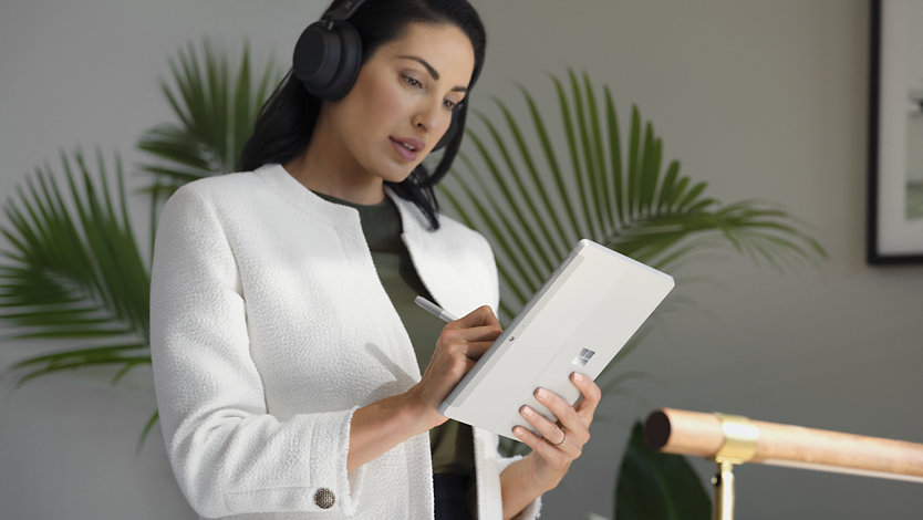 Uma pessoa a utilizar uma Caneta para Surface para Empresas para escrever no ecrã tátil de um Surface Go 4 para Empresas.