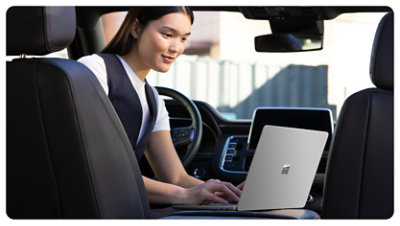 A person parked in a car uses a Surface Laptop for Business, suggesting how the anti-reflective screen allows for easy use in all kinds of environments.