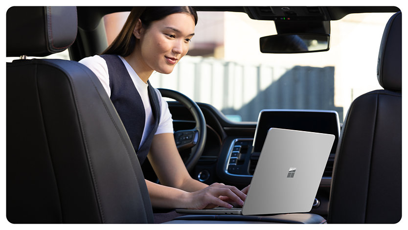 A person parked in a car uses a Surface Laptop for Business, suggesting how the anti-reflective screen allows for easy use in all kinds of environments.