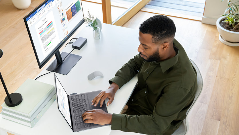 Une personne utilise un appareil Surface Laptop 5 pour les entreprises alors qu’elle est assise à son poste de travail dans un bureau. 