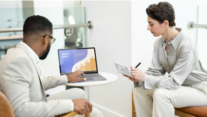 Two co-workers look at Surface Laptop 5 for Business while taking notes.