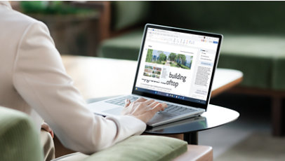 Henkilö kirjoittaa platinanvärisen Surface Laptop 6 yrityksille -laitteen näppäimistöllä.