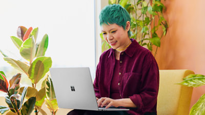 A smiling student uses a Surface Laptop.