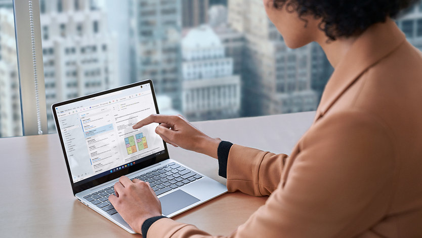 A person uses the touchscreen of a Surface Laptop Go 3 for Business, representing that Windows 11 Pro is now better optimized for the touchscreen.