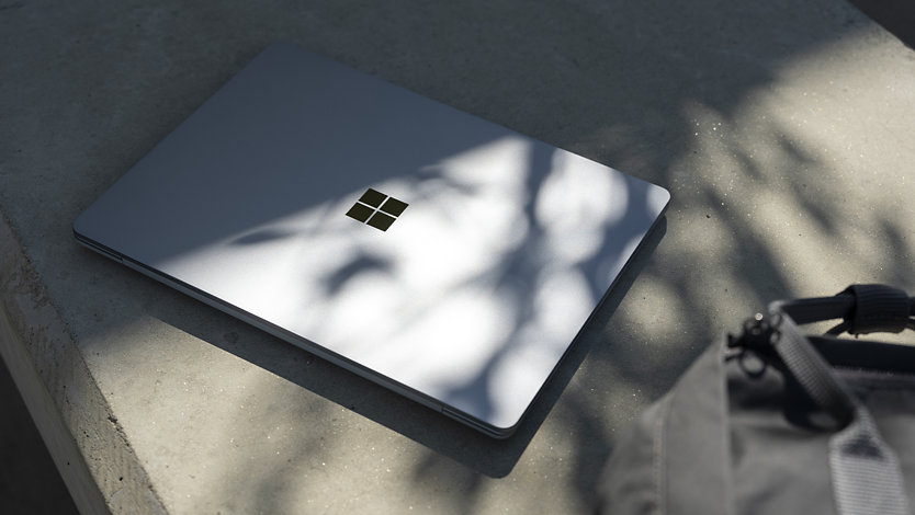 Un Surface Laptop Go 3 pour les entreprises est montré en extérieur, suggérant la durabilité de l’appareil et son optimisation pour le travail nomade.