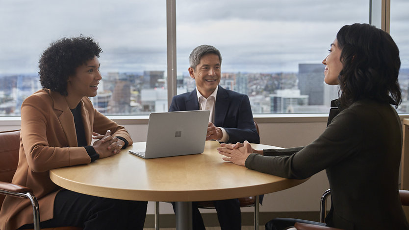 Menschen verwenden Surface Laptop Go 3 for Business während eines Meetings im Büro, was auf die Benutzerfreundlichkeit in einem professionellen Umfeld hinweisen soll.