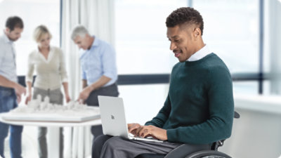 A person in a wheelchair types on a Surface Laptop for Business resting in their lap.