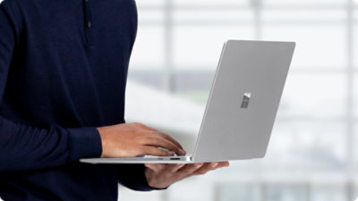 A close-up of a person holding a Surface Laptop for Business.