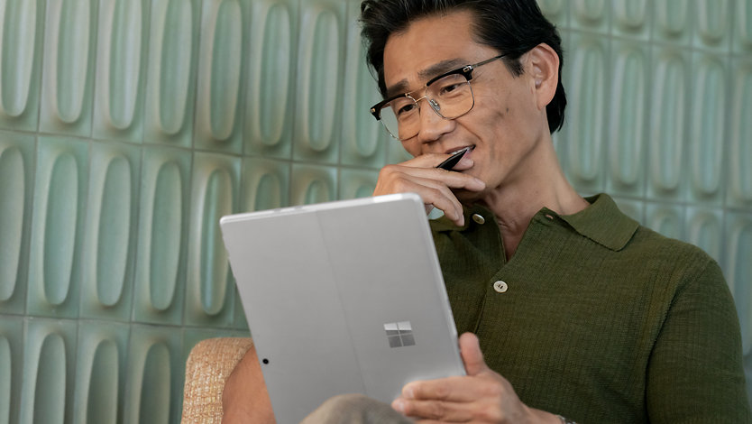 A man reads something on his Surface Pro 10. 