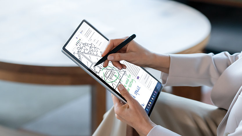 Una persona utilizza una Slim Pen per scrivere sul touchscreen di un Surface Pro 10 per le aziende di colore platino.