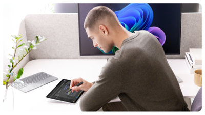 A person sits at a desk and makes handwritten notes on their Surface Pro for Business using Surface Slim Pen. 