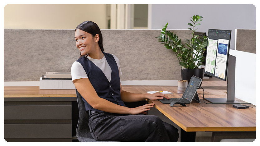 A person in an office smiles using a Surface Pro for Business.