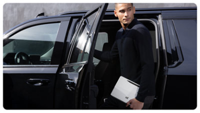 Una persona tiene in mano un Surface Pro per le aziende mentre scende da un'auto.