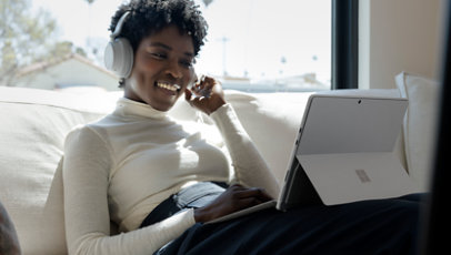 A woman using a Surface Pro 8 and Surface Headphones.