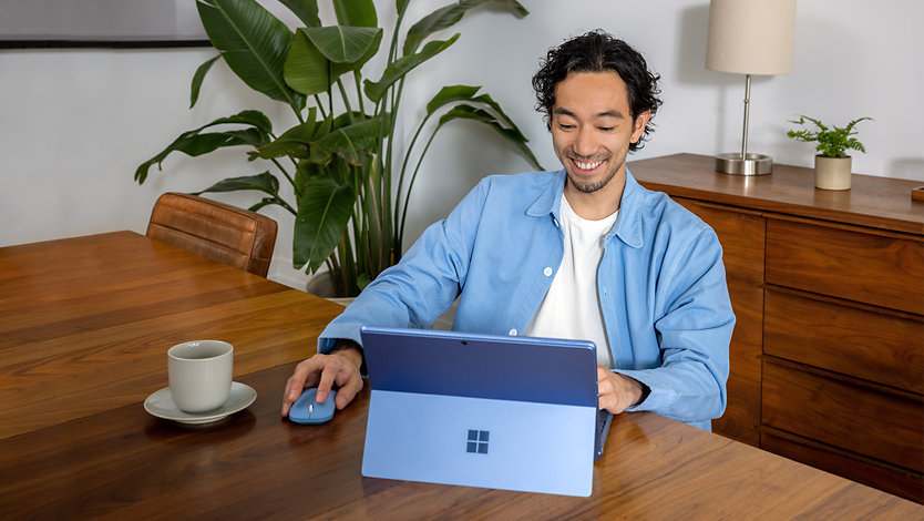 Henkilö työskentelemässä työpöydän ääressä Surface Pro 9:llä ja Microsoft Modern Mobile Mouse -hiirellä.