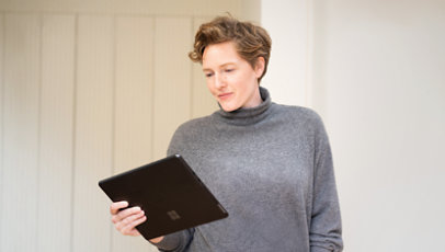 A customer holding a black Surface Pro 9 while studying its screen.