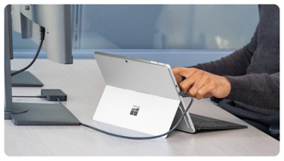 Une personne connecte une Surface Pro à un appareil Station d’accueil Surface USB4 pour les entreprises, sur son bureau.