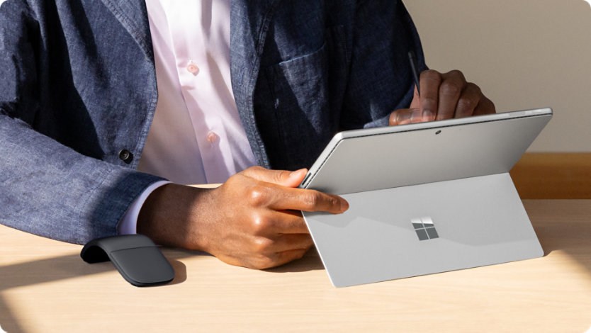 Uma pessoa a utilizar um Surface Pro para Empresas com o suporte Kickstand integrado aberto.