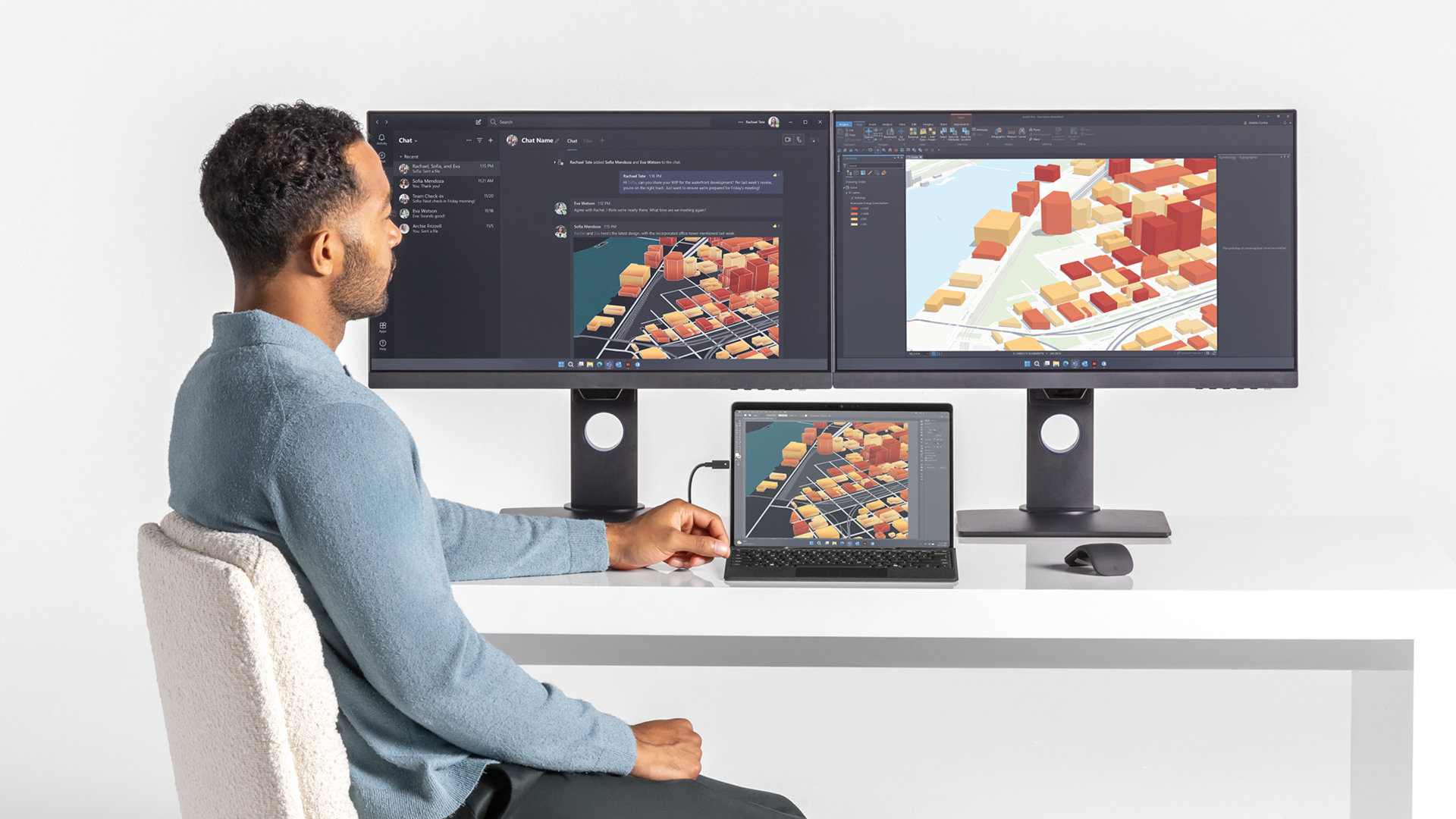 Une personne assise à un bureau utilise une Surface Pro connectée pour travailler sur plusieurs écrans.
