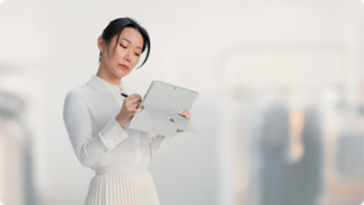 A person holds a Surface Pro for Business while writing on the touchscreen with Slim Pen. 