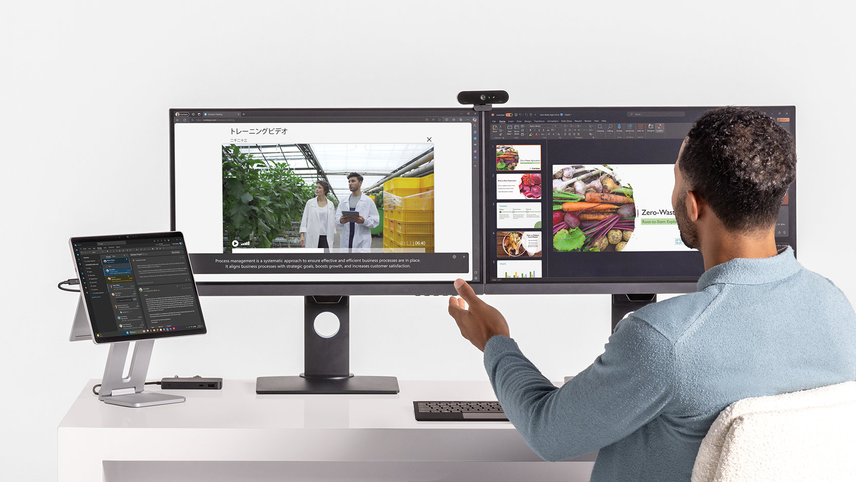 A person works at their desk featuring a Surface Pro and two external monitors all connected via Surface USB4 Dock for Business.