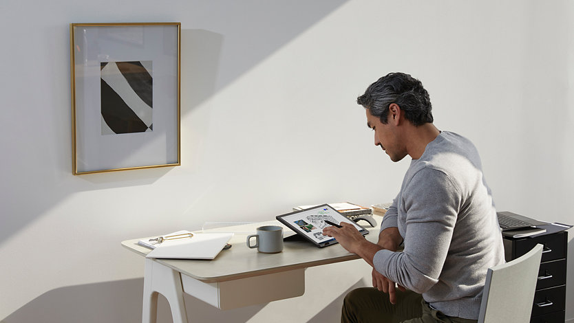 A person uses a Surface for Business device while sitting at a desk.