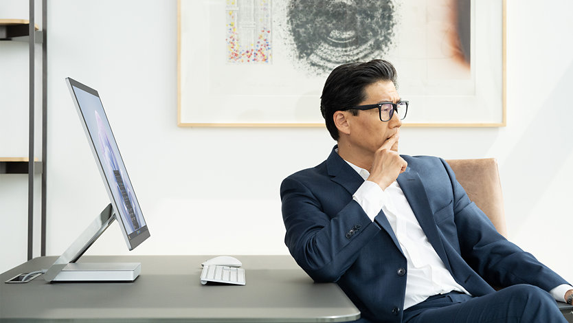 Une personne utilise un appareil Surface pour les entreprises alors qu’elle est assise à son poste de travail dans un bureau.