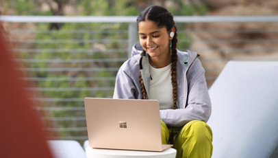 A person using a Surface Laptop 5 outdoors.