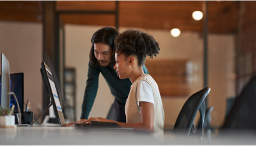 Coworkers look at SharePoint on a computer monitor in an office.