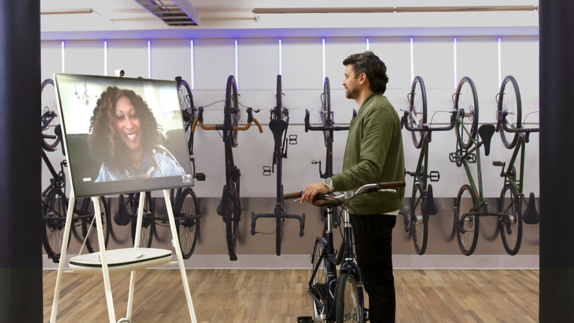 A bike shop employee uses Microsoft Teams to demo products for a customer. 