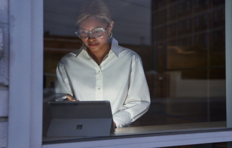 Một người phụ nữ đang sử dụng máy tính bảng trước cửa sổ.