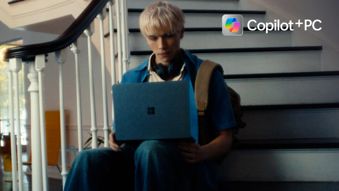 A young man sitting on a staircase using his Surface PC