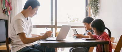 A family sitting at a table using a laptop.