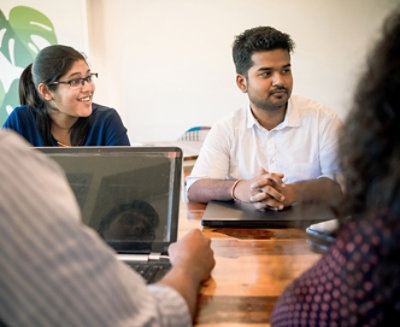 A group of people sitting around a table with laptops.