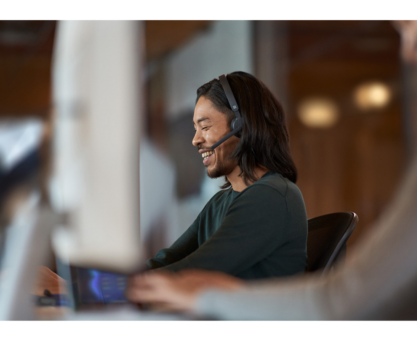 Ein Mann trägt ein Headset, während er an einem Computer arbeitet.