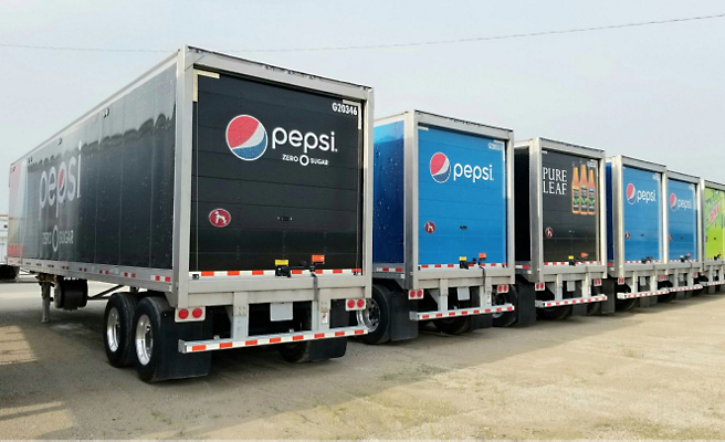 Uma fila de camiões da Pepsi num parque de estacionamento.