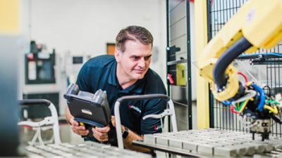 Un hombre trabajando con un robot en una fábrica.