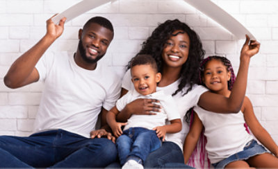 Una familia sentada en el suelo delante de una casa.