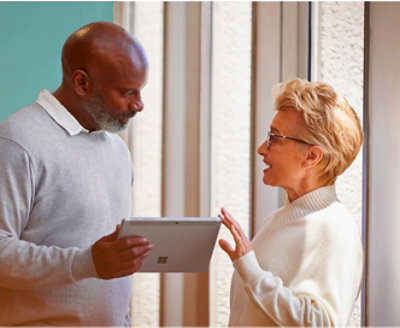 Two persons are discussing while on of them is holding a tablet