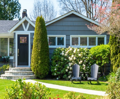 A house with green lawn in front with patio chairs