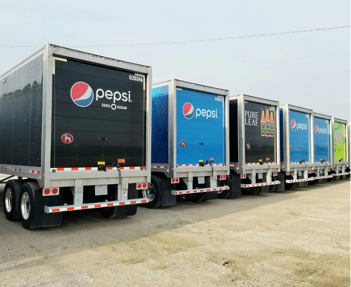 Baksidan av flera lastbilar med Pepsi målad på dem
