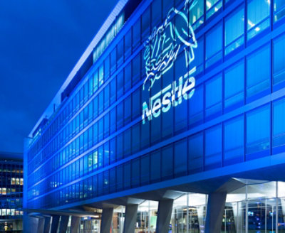 A building lit up at night with a Nestle logo on it