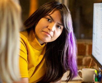 A woman in yellow sweater and a slight shade of purple in her hair
