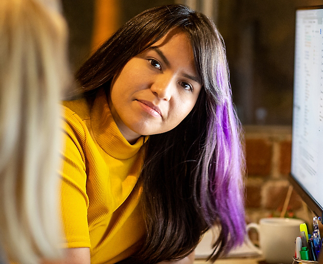 A woman in yellow sweater and a slight shade of purple in her hair